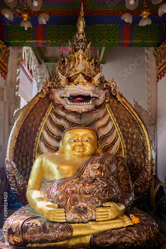 The golden Maha Katyayana Buddha image covered with a serpent behind it is located inside the temple. photo