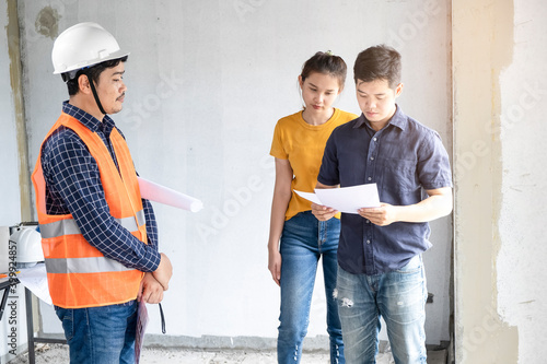 Young asian couple checking house with foreman engineering home inspection building house Walk home inspection with looking and pointing construction check building home on job site construction 2021