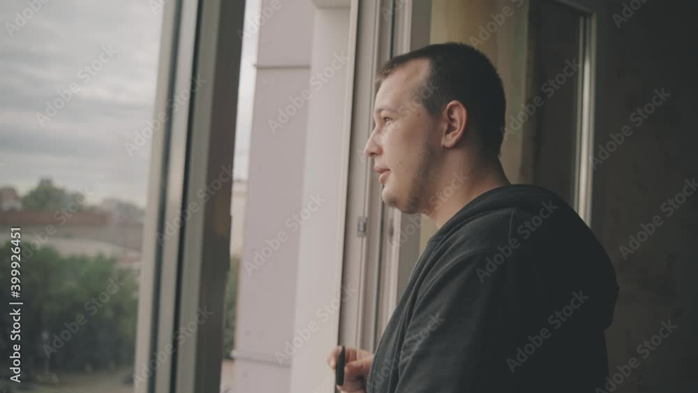 Happy man on the balcony at home looking into the distance through the window Happy man on the balcony at home looking into the distance through the window