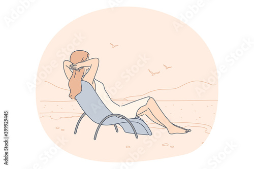 Summer, vacation, relax concept. Woman sitting on beach chair and looking at calm sea and seagulls enjoying seaside recreation watching seascape. Holiday rest and summertime sunbathing on sand