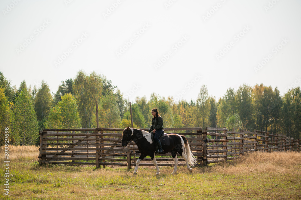A young girl enjoys the autumn nature while riding a horse outside the city. A young girl enjoys the autumn nature while riding a horse outside the city.