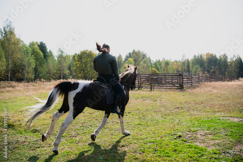 A young girl enjoys the autumn nature while riding a horse outside the city.