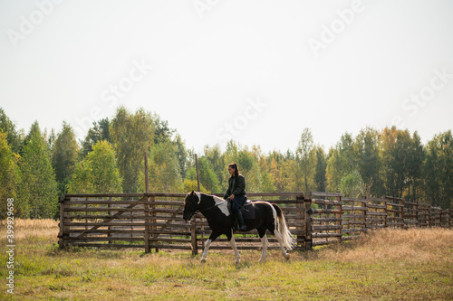 A young girl enjoys the autumn nature while riding a horse outside the city.