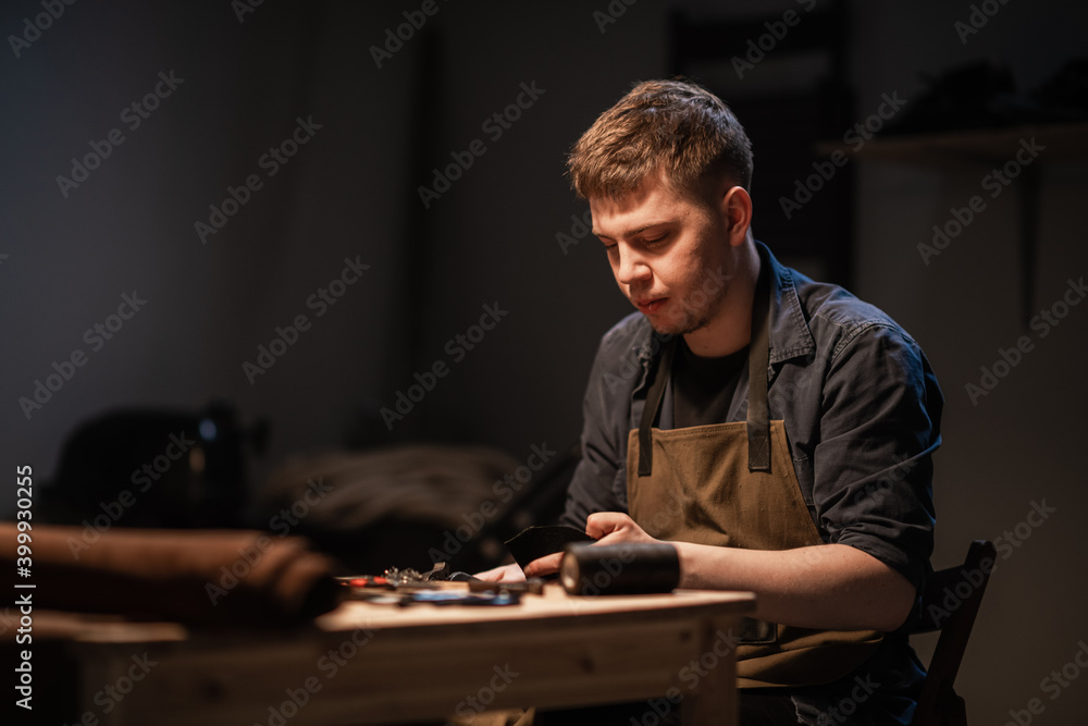 a young talented shoemaker in the workshop is engaged in manual production of shoes made of leather a young talented shoemaker in the workshop is engaged in manual production of shoes made of leather