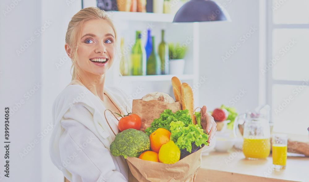 Young woman holding grocery shopping bag with vegetables Standi Young woman holding grocery shopping bag with vegetables Standi