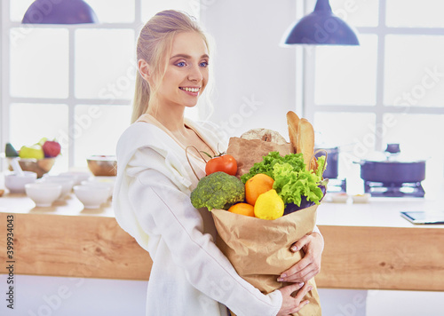 Young woman holding grocery shopping bag with vegetables Standi