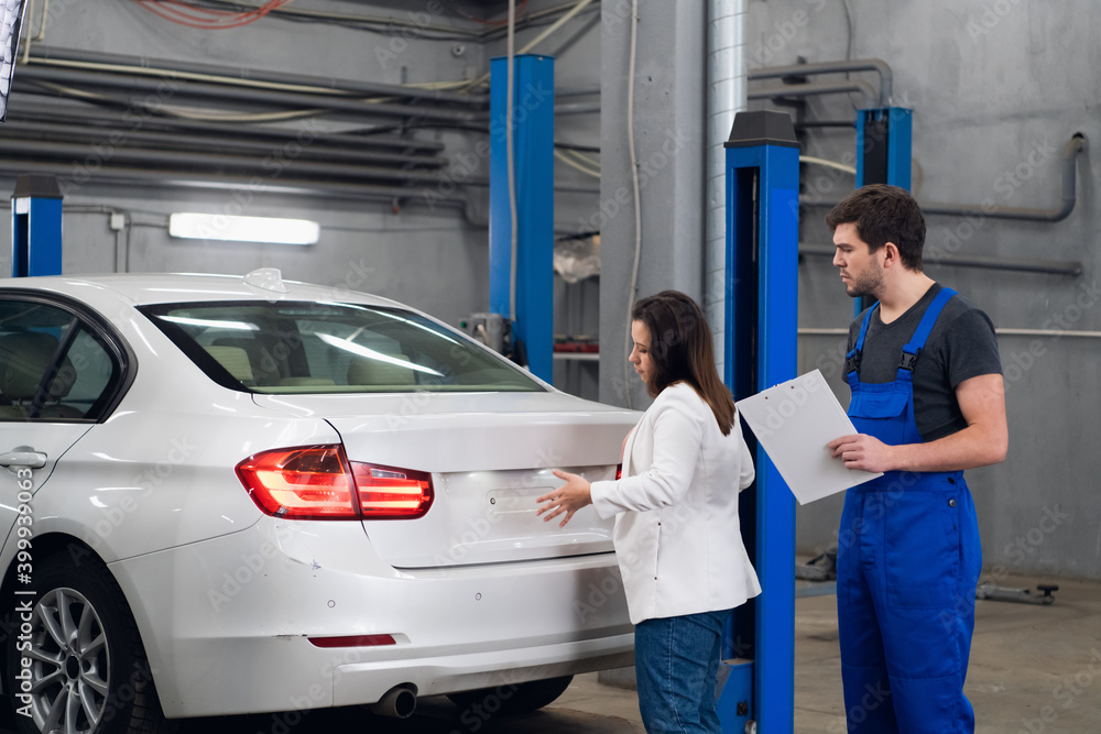 Worker tells the customer about the repair of a car Worker tells the customer about the repair of a car