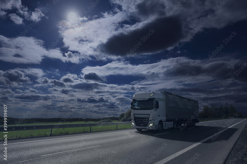 White truck driving on highway through night landscape at moonlight