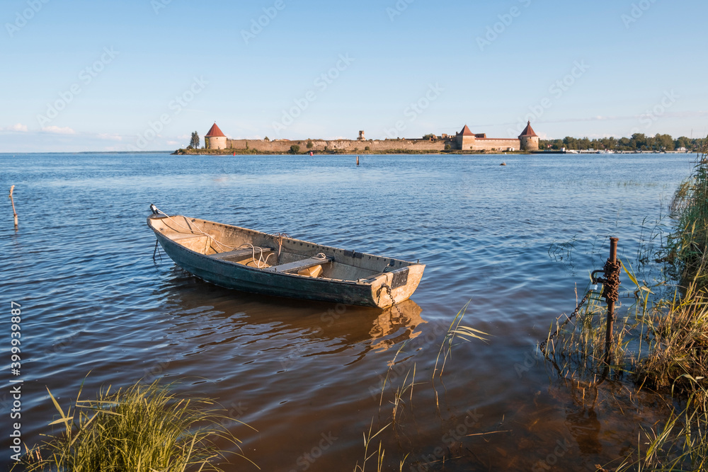 Old fishing boat on the background of the Oreshek fortress in Shlisselburg, Russia on a sunny summer day