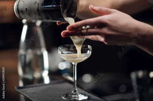 An experienced bartender prepares an alcoholic cocktail. No face, close-up, copy space