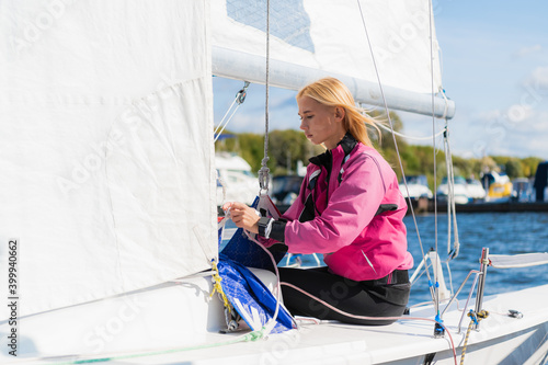 Young athletic girl in sports clothes on a yacht in the dock is ready for a sailing regatta