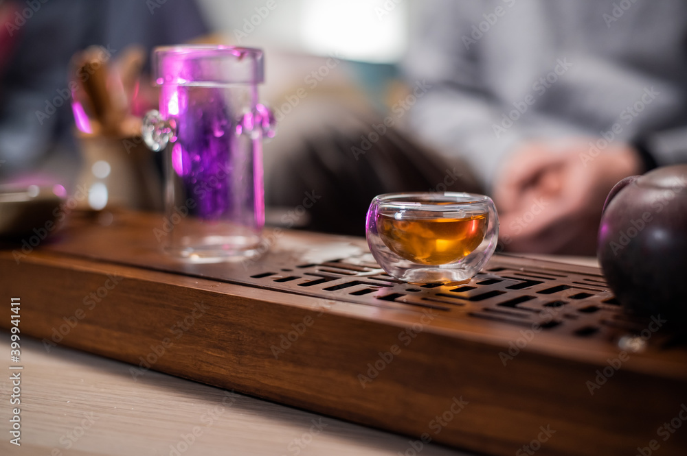 Glass cup and flask for tea on a bamboo board with a tray. Close-up of the tea ceremony on the table