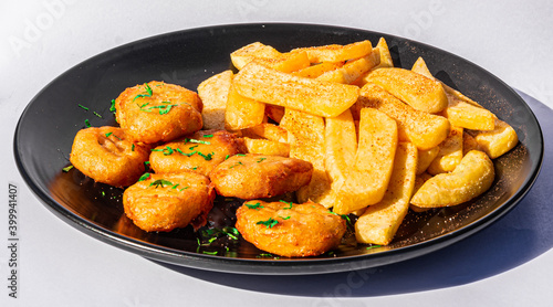plate of chicken nuggets with french fries on dark background, top view