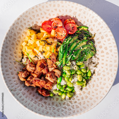 Hawaiian chicken poke bowl with rice, edamame, mango, cherry tomatoes, avocado, sesame seeds and seaweeds. Buddha bowl. Diet food