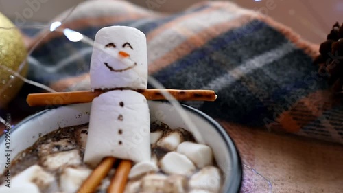 A cup of cocoa with marshmallows and Olaf the snowman. A funny snowman bathes in hot chocolate. Christmas mood, New Year's winter drink.