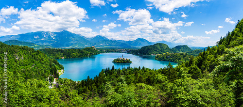Beautiful iconic landscape of Lake Bled with the church island in the middle, the castle in the background and white clouded sky as seen from Ojstrica viewpoint in Bled, Slovenia