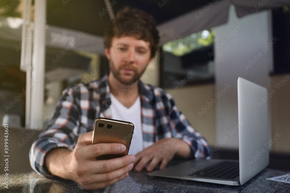 Handsome man using smartphone at table in cafe, focus on hand Handsome man using smartphone at table in cafe, focus on hand