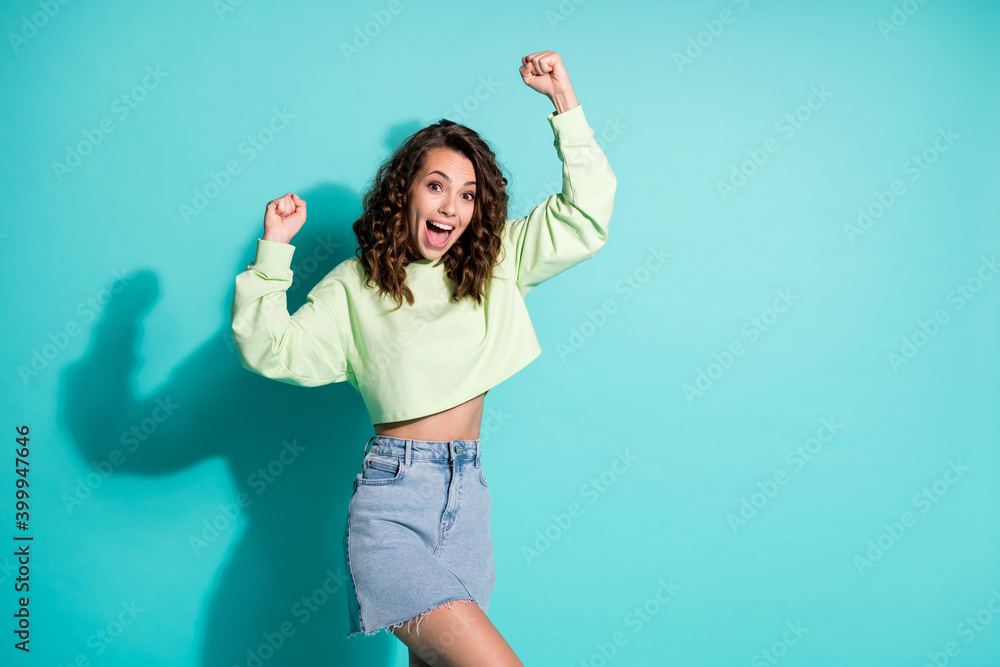 Naklejka premium Photo of happy yell young lady raise fists dressed green pullover denim skirt isolated on turquoise color background