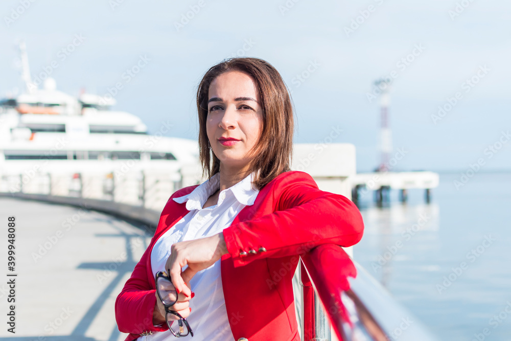 Obraz premium business woman in a red suit stands by the sea