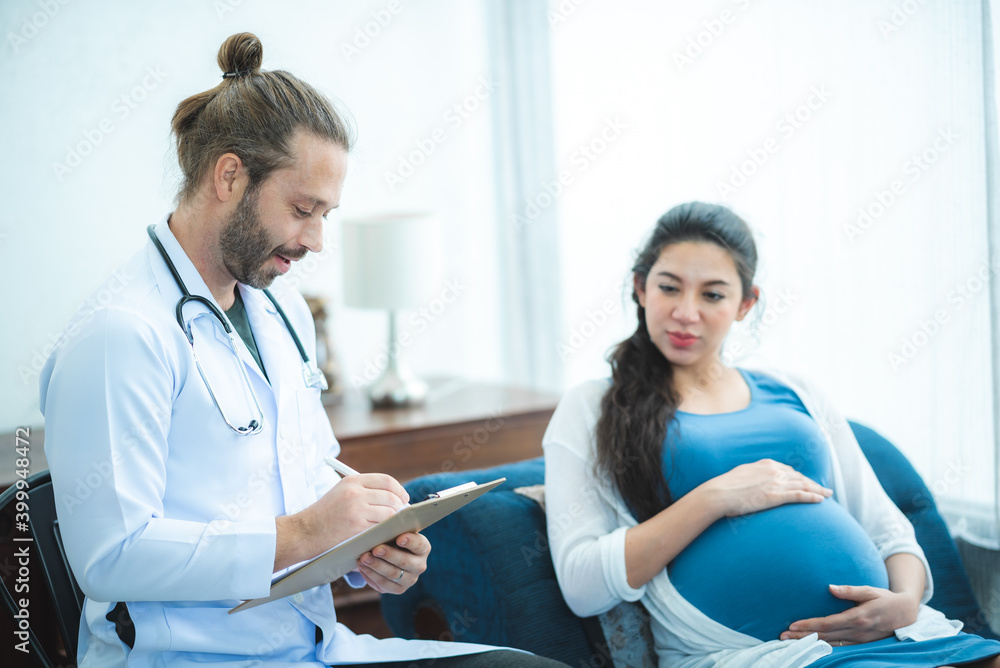Fototapeta premium Young pregnant couple looking at ultrasound image.