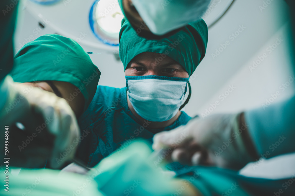 professional surgery team in the operating room, urgent surgery. Professional smart intelligent surgeons standing near the patient and performing an operation while saving his life professional surgery team in the operating room, urgent surgery. Professional smart intelligent surgeons standing near the patient and performing an operation while saving his life