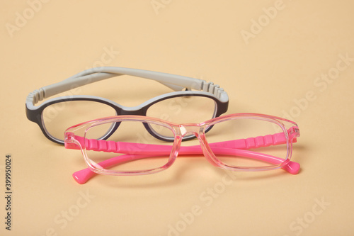 two pairs of children's glasses on a beige background