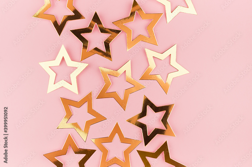 Bright gold glossy stars on soft light pink color, top view, border. Bright gold glossy stars on soft light pink color, top view, border.