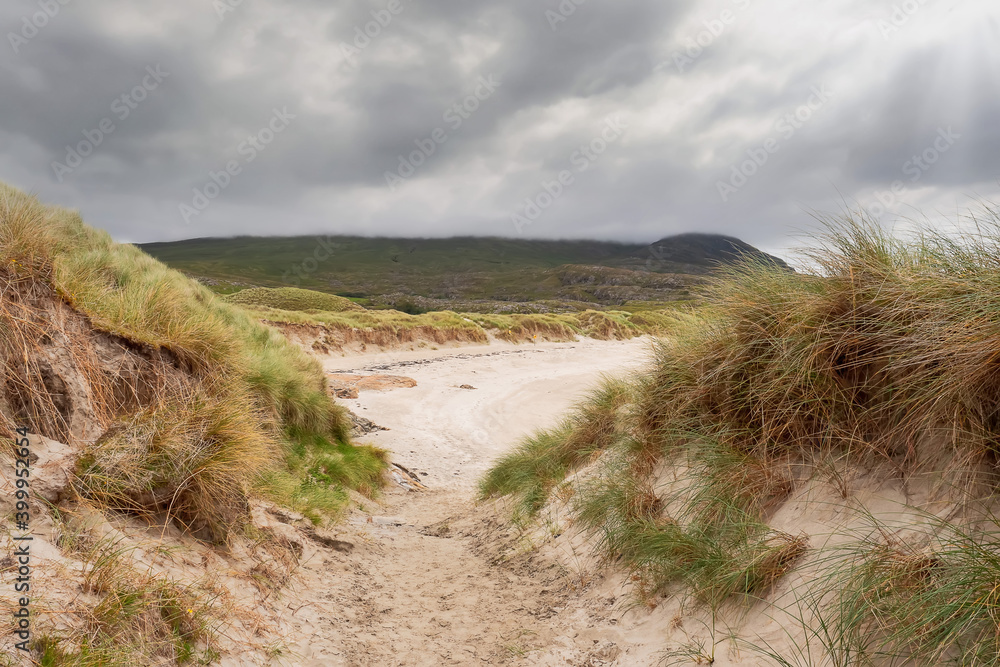 Sandy beach and dunes on West coast of Ireland. Selective focus.Cloudy sky Sandy beach and dunes on West coast of Ireland. Selective focus.Cloudy sky