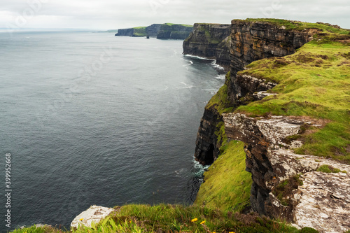 Beautiful view on Cliff of Moher, county Clare, Ireland. Popular tourist landmark and destination with epic nature landscape.Calm Atlantic ocean and cloudy sky
