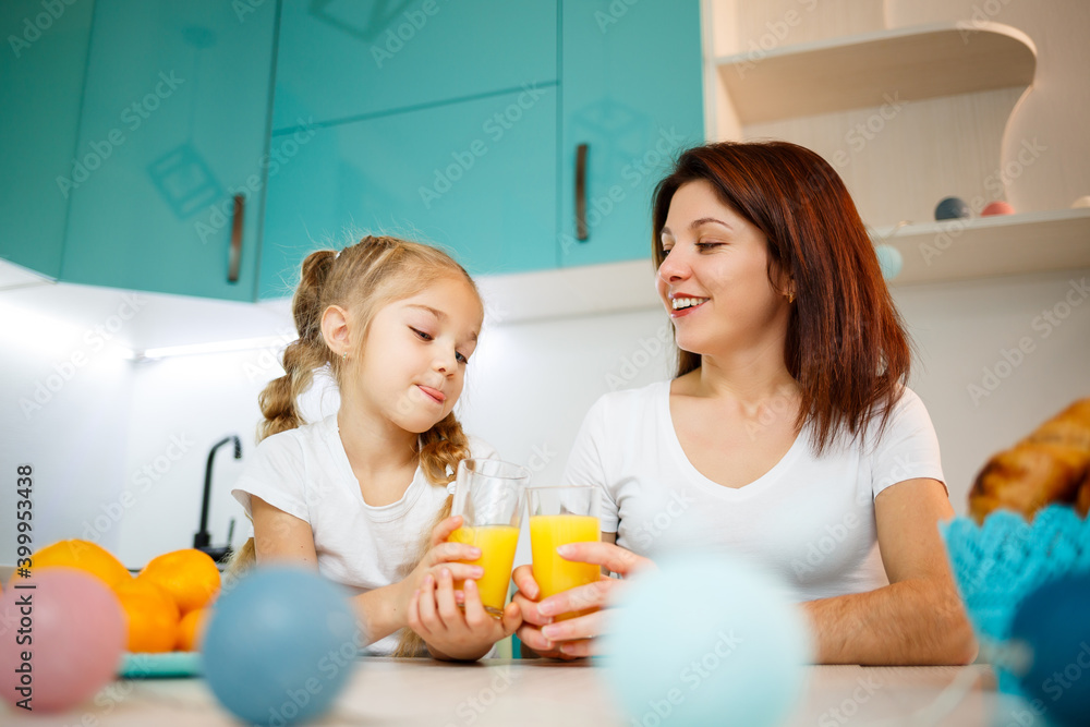 Mother with little girl drinking orange juice while they have breakfast together Mother with little girl drinking orange juice while they have breakfast together