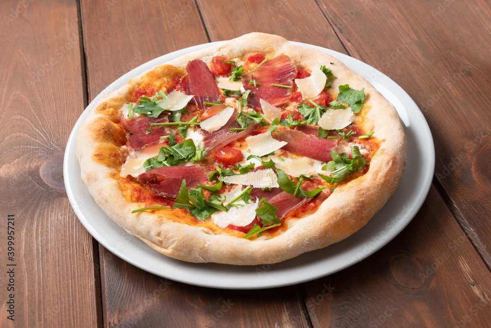 Deliziosa pizza italiana condita con fettine di lonza di maiale, rucola e grana 