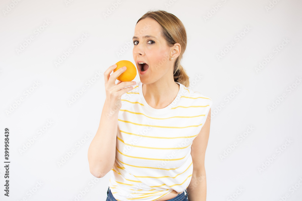 Young woman isolated on white background eating an orange Young woman isolated on white background eating an orange