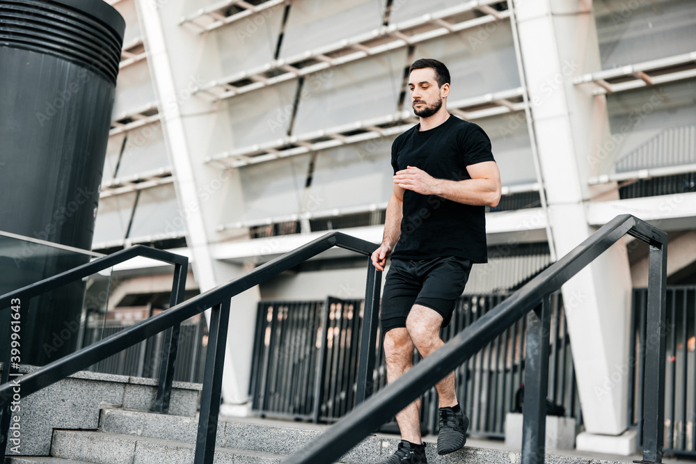 © Ivan - Athletic young man running down from stairs. Urban sport concept. Apartment block on background. Active living. Outdoor fitness. Man in black sportswear jogging at morning. © Ivan - Athletic young man running down from stairs. Urban sport concept. Apartment block on background. Active living. Outdoor fitness. Man in black sportswear jogging at morning.