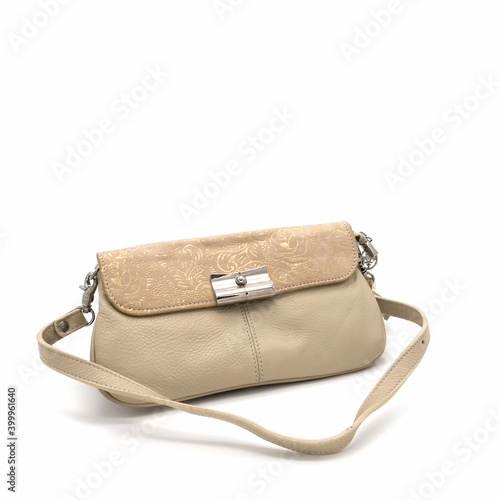 Women's clutch bag made of genuine beige leather. The valve is decorated with a golden floral ornament. Metal clasp. Long shoulder strap. Isolated on a white background.