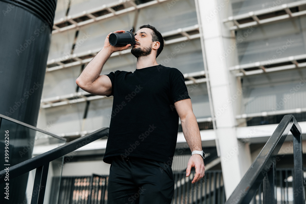 Hydration time Man drinking water from sports bottle after jogging. Hard workout. Take care of youself concept. Drink more water. Don't forget to drink during training.