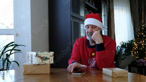 beared senior man in red christmas hat talking on the smart phone, video call