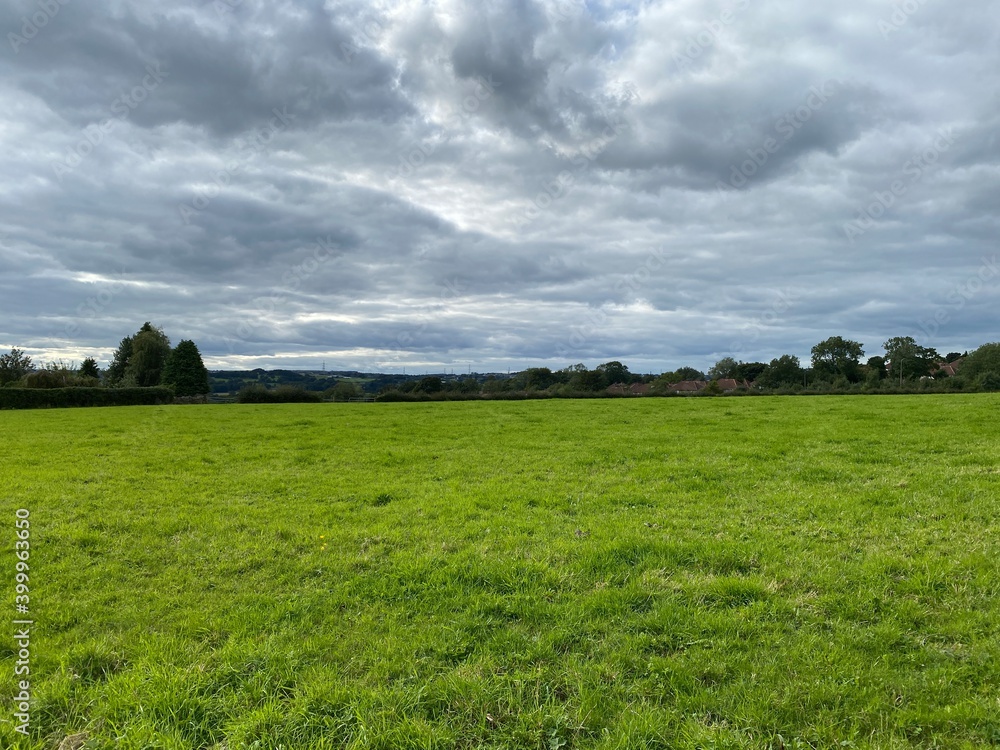 Large flat green plain, with trees on the horizon, and heavy rain clouds above in, Lower Wyke Road, Bradford, UK Large flat green plain, with trees on the horizon, and heavy rain clouds above in, Lower Wyke Road, Bradford, UK