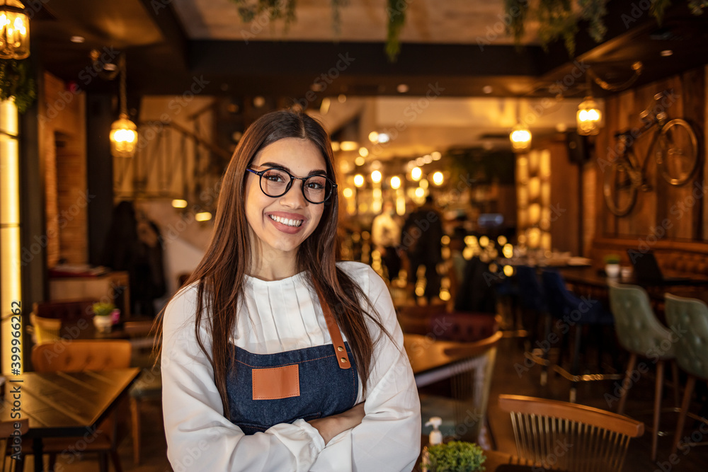 Portrait of a beautiful waitress wearing an apron, smiling at camera. Portrait of positive young woman working professional confectioner in own coffee shop, looking at camera with toothy smile. Portrait of a beautiful waitress wearing an apron, smiling at camera. Portrait of positive young woman working professional confectioner in own coffee shop, looking at camera with toothy smile.