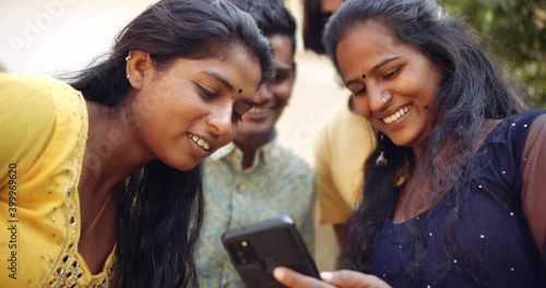 Slow-motion close-up CU portrait of four friends as they look at a smart phone mobile screen as laugh out loud and smile as they have a good time enjoy sharing and bonding 