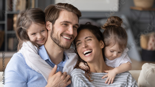 Close up wide banner panoramic view of happy young Caucasian family with two small daughters have fun at home. Smiling mom and dad feel playful enjoy weekend relaxing with little girls children.