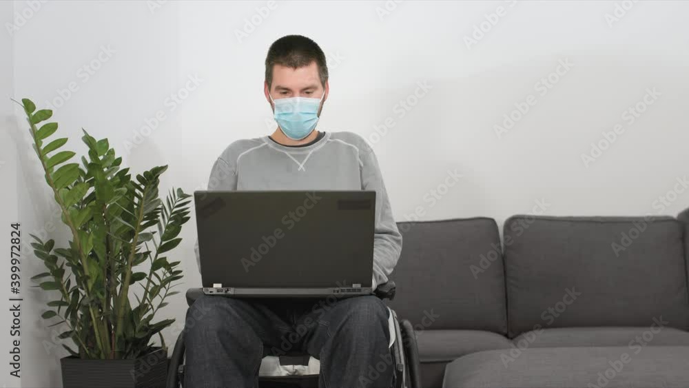 Man on wheelchair remotely working from home using laptop, looking at screen with virtual web chat. Man on wheelchair remotely working from home using laptop, looking at screen with virtual web chat.