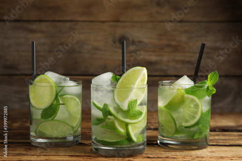 Delicious mojito and ingredients on wooden table