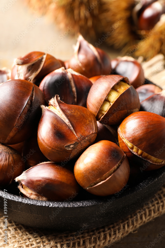 Obraz premium Tasty roasted edible chestnuts on table, closeup