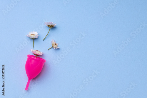 Menstrual cup with flowers on blue background © fotofabrika