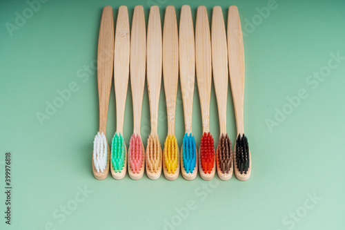 A set of Eco-friendly antibacterial toothbrushes made of bamboo wood on a light green background. Environmental care trends © Kate