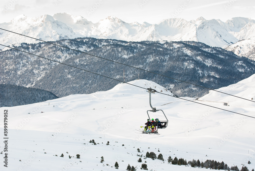 Paisaje invernal de alta montaña con esquiadores montados en telesilla.