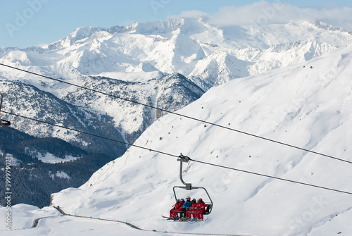 Paisaje invernal de alta monta  a con esquiadores montados en telesilla.