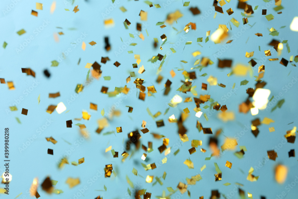 Shiny golden confetti falling down on light blue background Shiny golden confetti falling down on light blue background