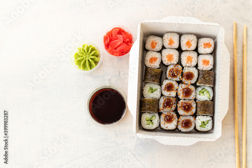Mixed sushi in box. Japanese sushi food in box on white background with copy space. Top view of sushi in box with ginger, soy and wasabi.