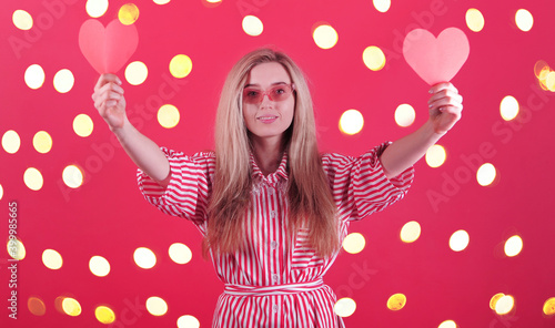 Valentine`s Day concept. Smiling woman with red heart in hand posing on red background. 